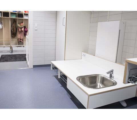 CE-mærket puslebord til institutioner 1300 x 900 mm fra ST Skoleinventar, inkl trådløs fjernbetjening og underlimet vask placeret til højre (set forfra)